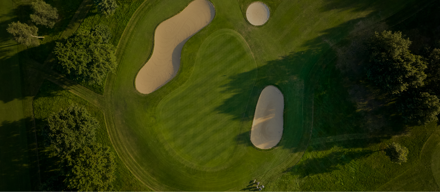 Aerial view of a golf course with green grass and sand bunkers.