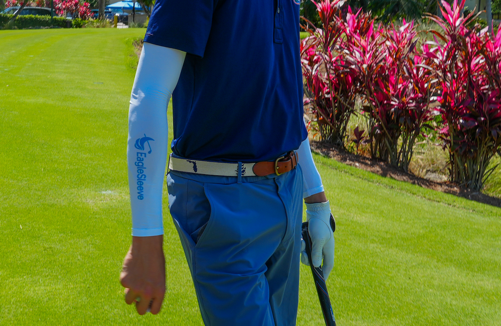 Person in blue golf attire on a golf course with pink foliage in the background